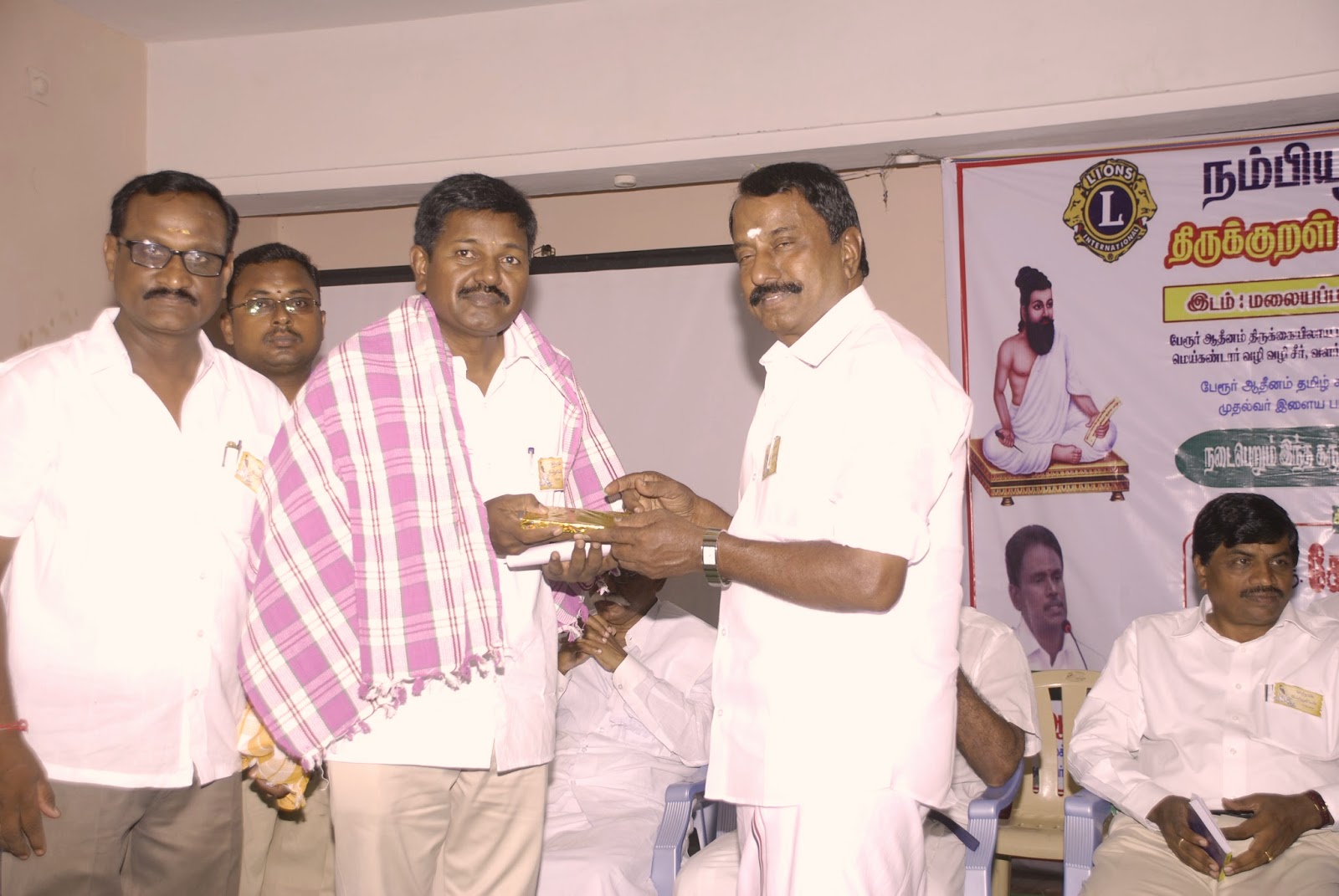 அவர்கள் திரு ரவிக்குமார் அவர்களுக்கு நல்லாடை அணிவிக்கிறார்.